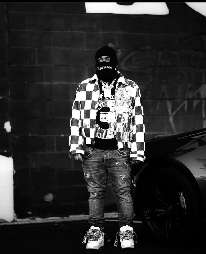 Black-and-white artist portrait beside a car