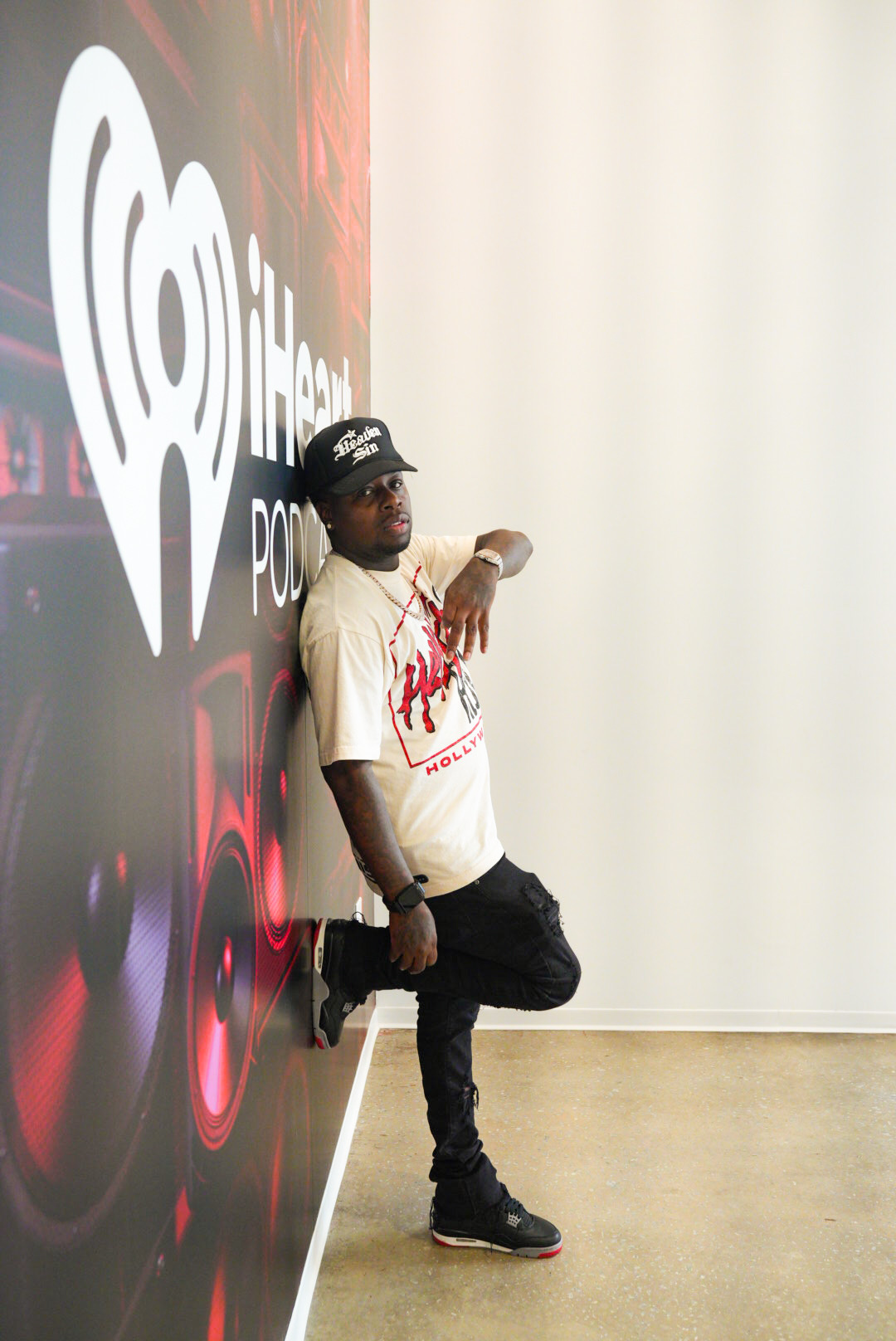Artist posing beside an iHeart wall